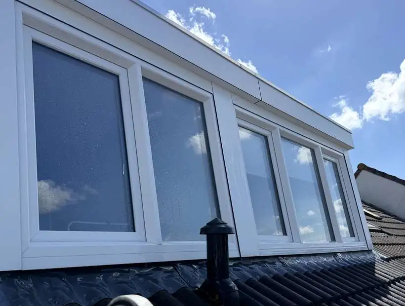 Schoongemaakte dakkapel met witte kozijnen tegen blauwe lucht